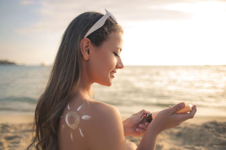 Mulher na praia aplicando protetor solar
