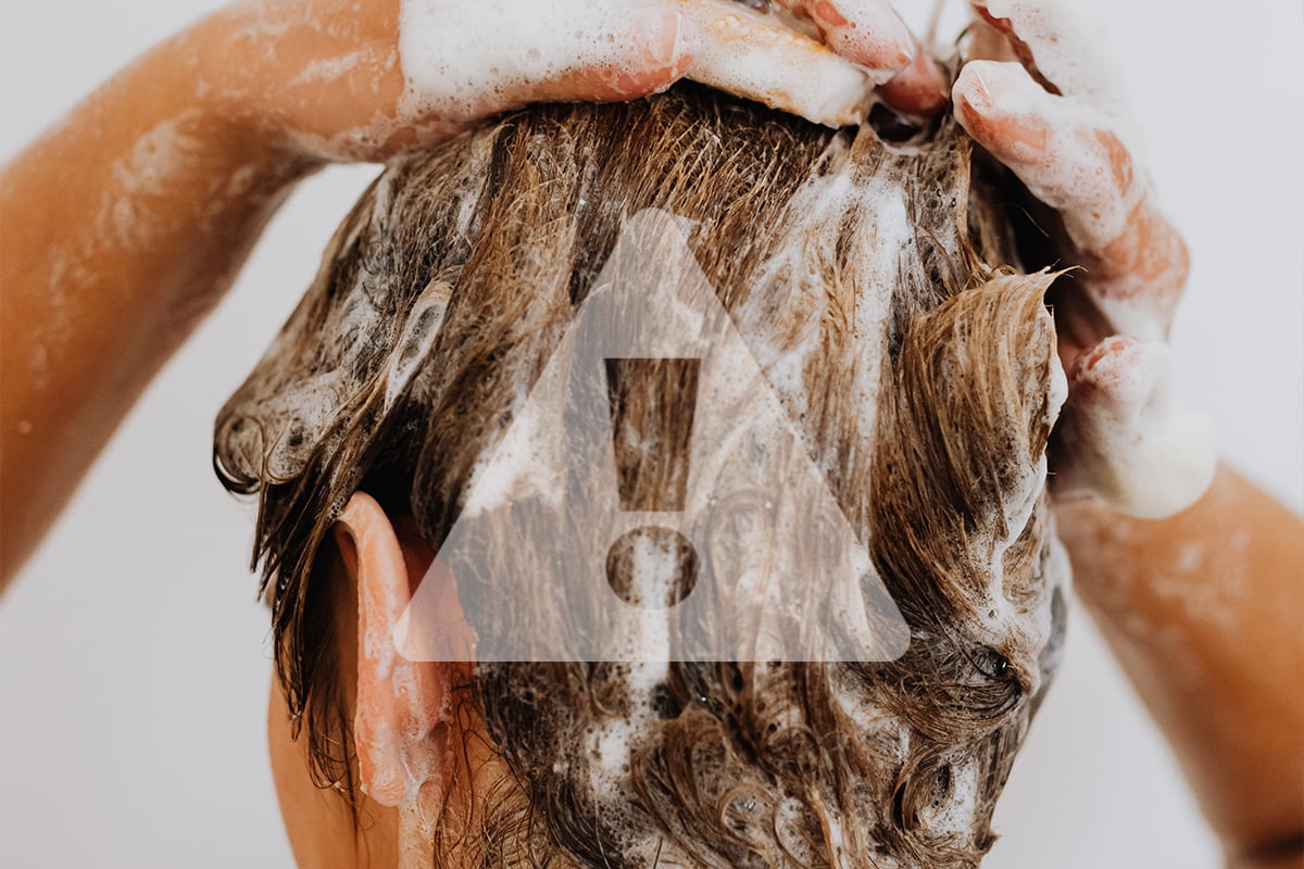 mulher lavando o cabelo com shampoo e um sinal de alerta para tomar cuidado com a quantidade