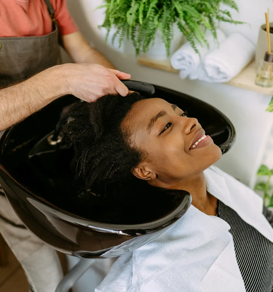 imagem de um cabeleleiro lavando o cabelo de uma mulher negra