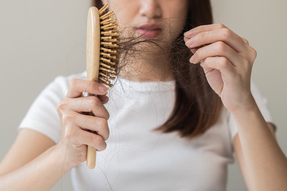 mulher com cabelo poroso caindo na escova