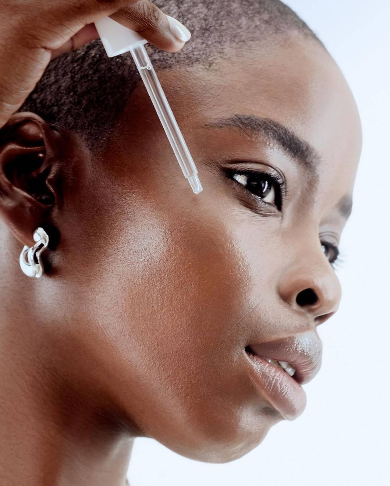 modelo com uma pele intacta aplicando sérum facial no rosto